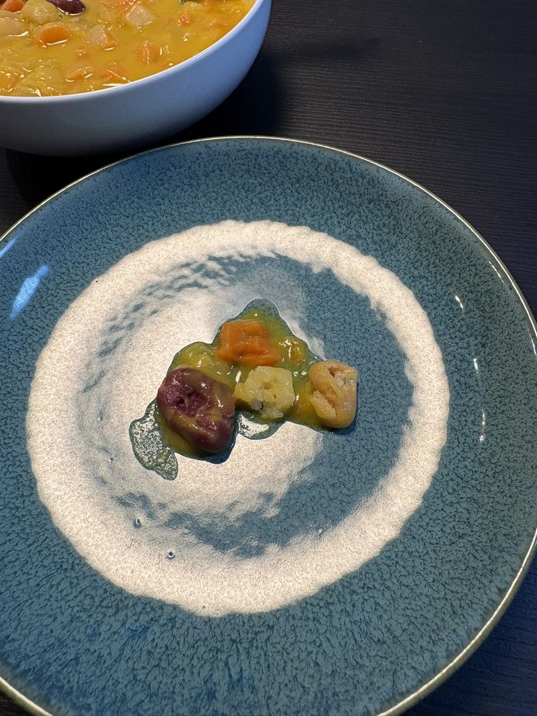 かぼちゃスープの具材（にんじん・じゃがいも・玉ねぎ・いんげん豆）を皿に取り出して箸で柔らかさを確認した写真
